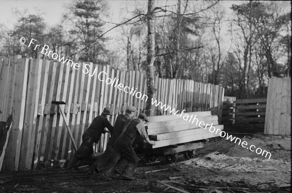 LUMBERING IN LEIX PILE OF WOOD WITH MEN IN FOREGROUND